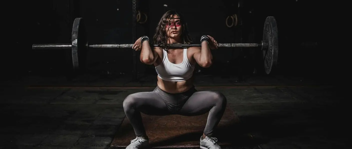 A woman performs a squat with a barbell