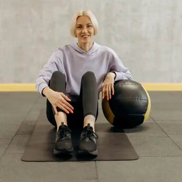 A personal trainer sits with a medicine ball