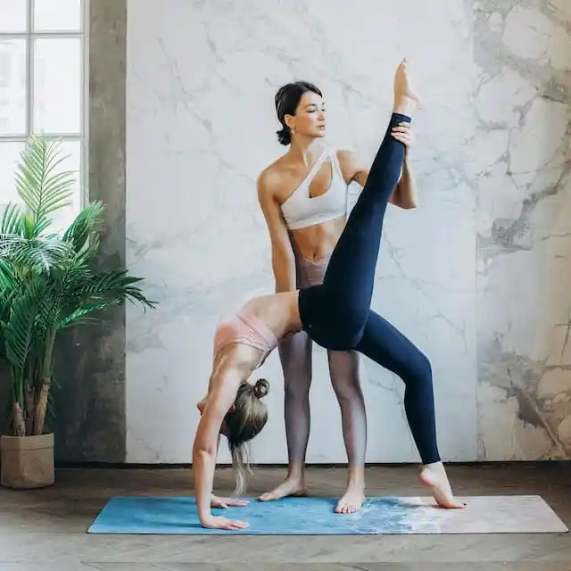 A trainer helps a woman with her flexibility