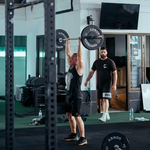 A trainer assesses a lifter's technique