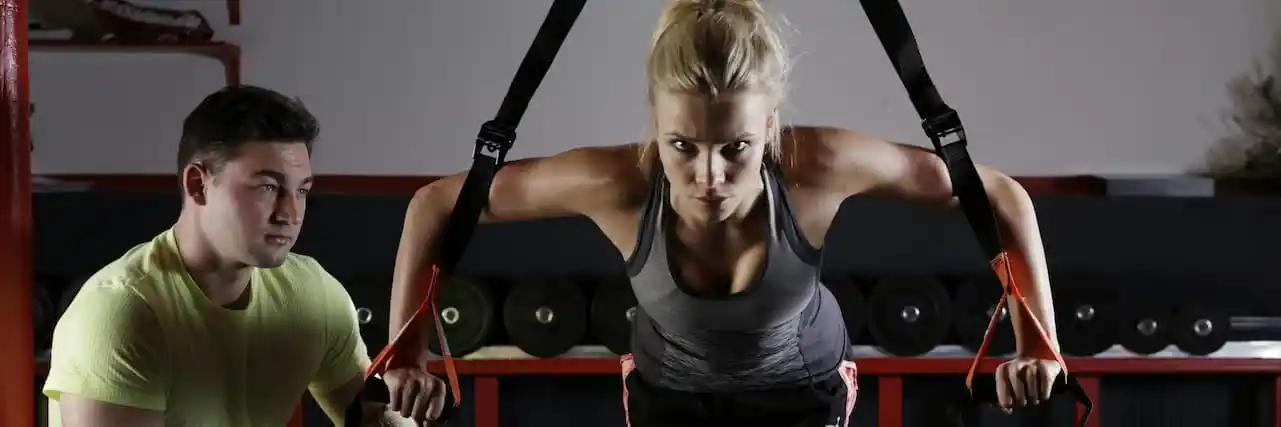 A trainer spots a woman's technique on functional equipment